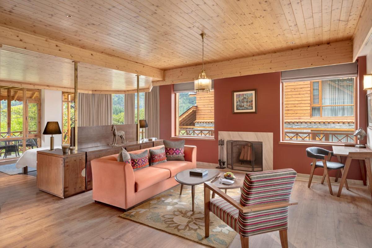 a living room with a couch and a fireplace at Welcomhotel By ITC Hotels, Hamsa Manali in Manāli a living room with a couch and a fireplace at Welcomhotel By ITC Hotels, Hamsa Manali in Manāli