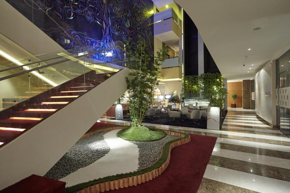 a lobby with a staircase and a tree in the middle at Turyaa Chennai - OMR IT Expressway in Chennai
