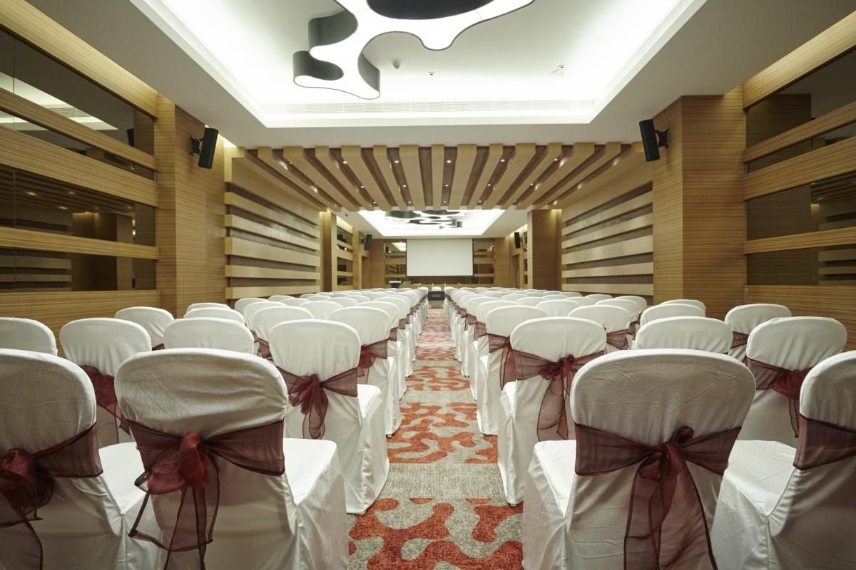 a row of chairs in a hall with white chairs at Turyaa Chennai - OMR IT Expressway in Chennai