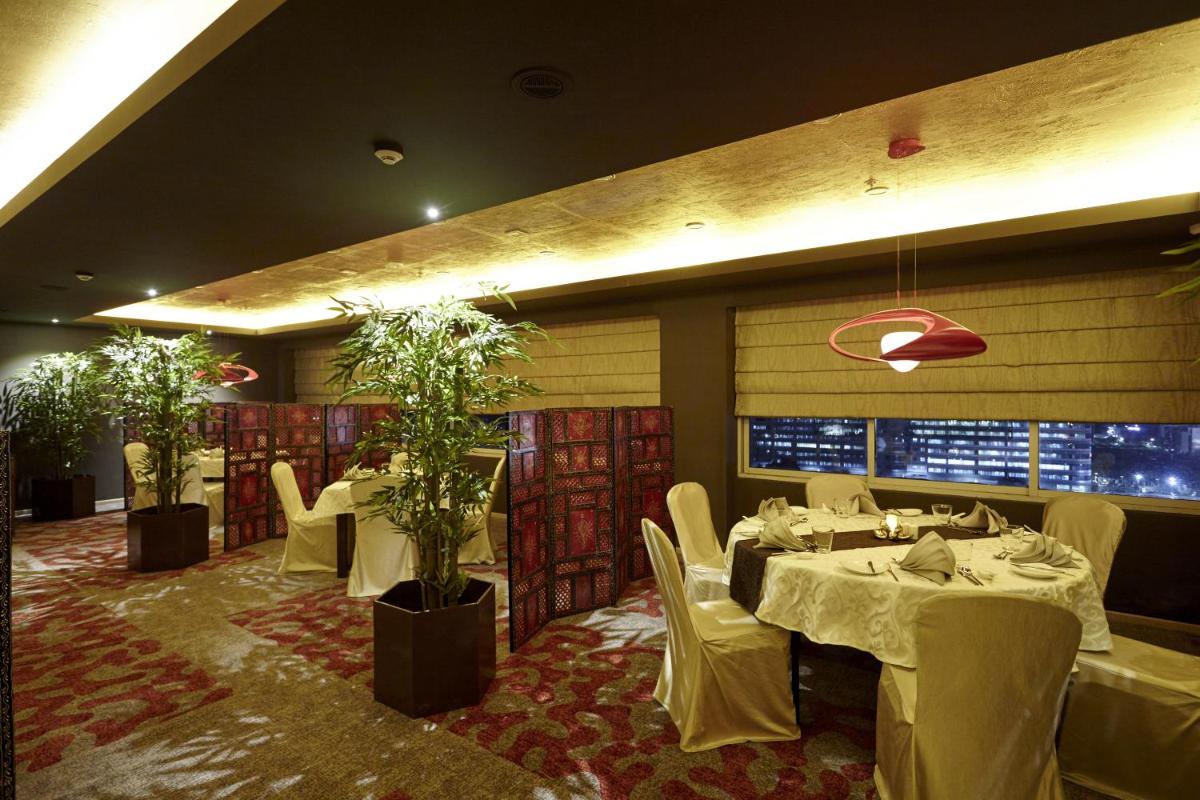 a restaurant with white tables and chairs and plants at Turyaa Chennai - OMR IT Expressway in Chennai