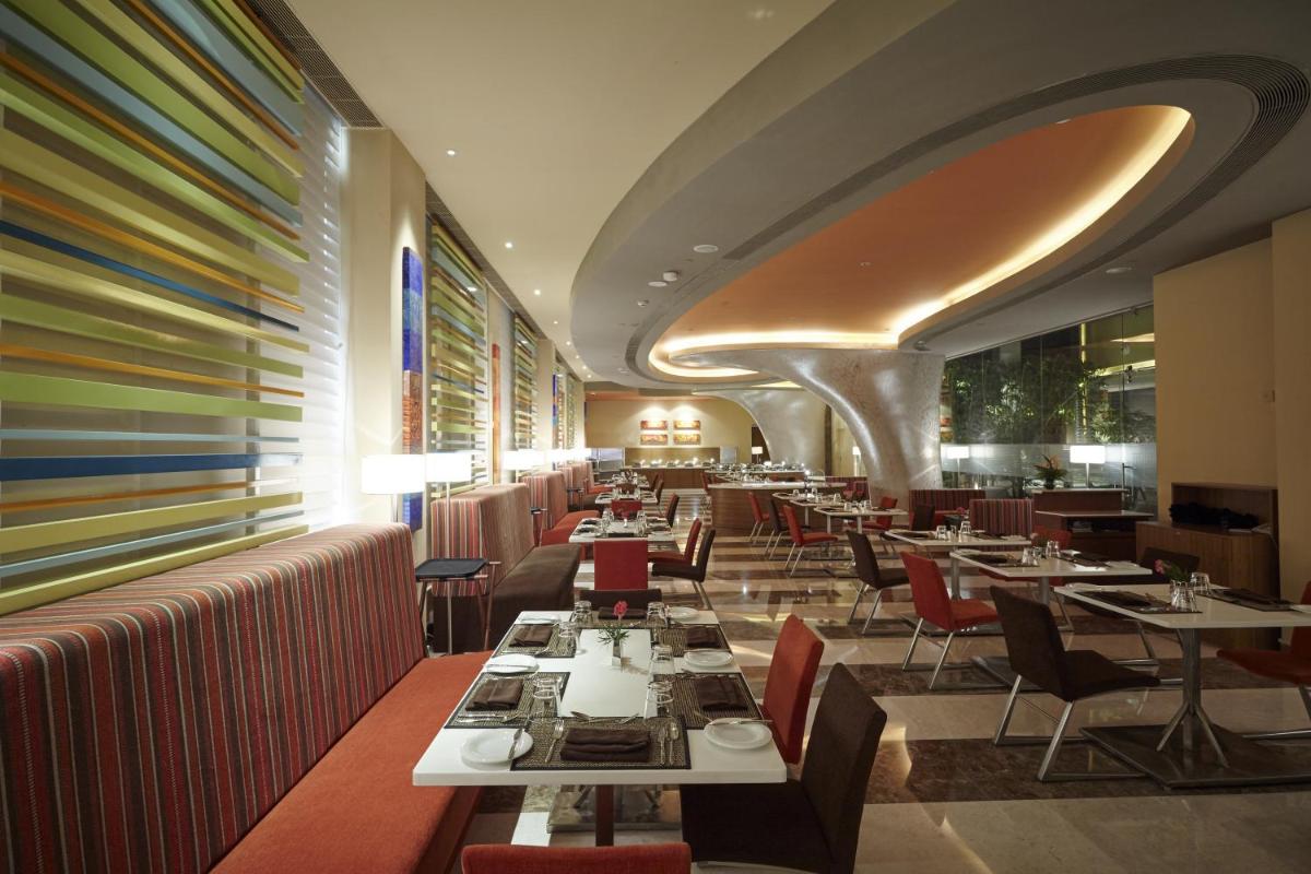 a restaurant with tables and chairs and a colorful wall at Turyaa Chennai - OMR IT Expressway in Chennai