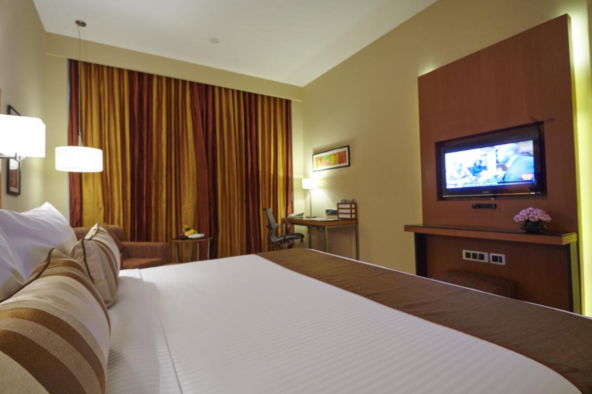 a hotel room with a large bed and a flat screen tv at Turyaa Chennai - OMR IT Expressway in Chennai
