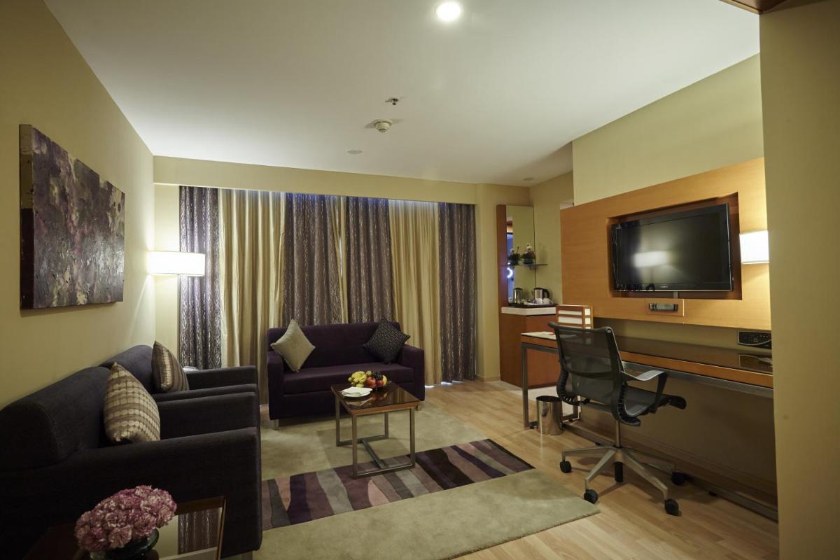 a living room with a couch a table and a television at Turyaa Chennai - OMR IT Expressway in Chennai