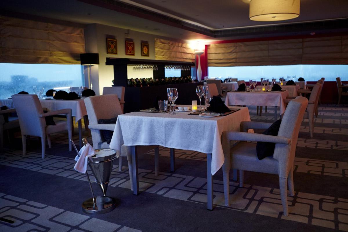 a dining room with tables and chairs and people in a restaurant at Turyaa Chennai - OMR IT Expressway in Chennai