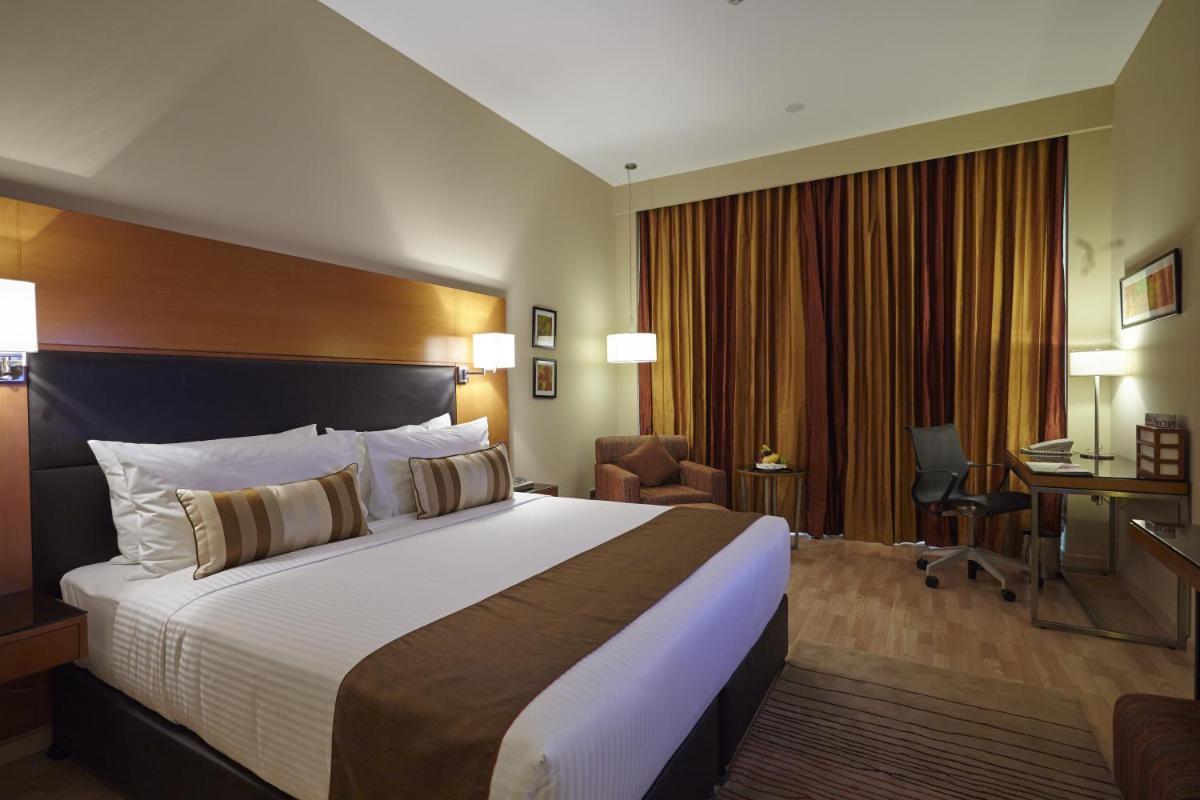 a hotel room with a large bed and a desk at Turyaa Chennai - OMR IT Expressway in Chennai