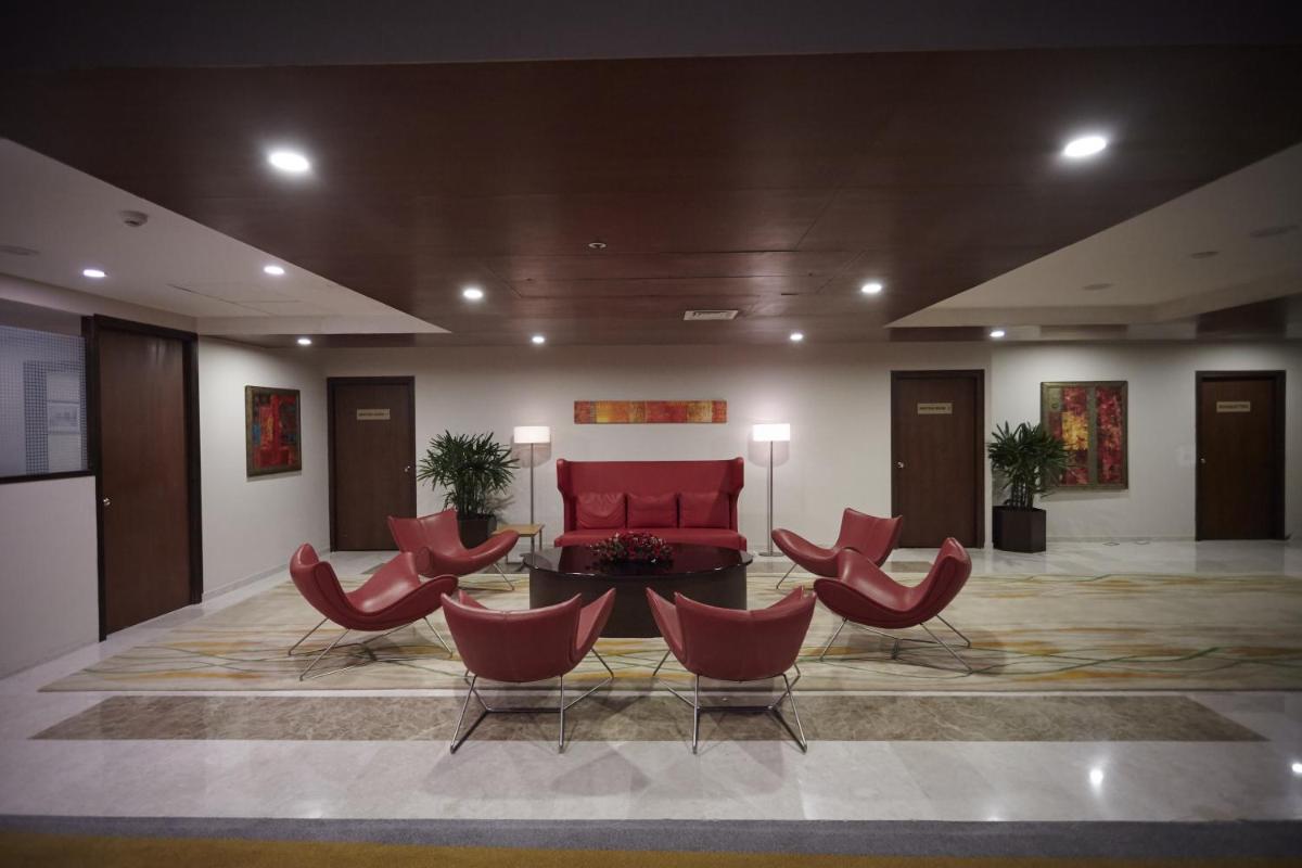 a lobby with red chairs and a red couch at Turyaa Chennai - OMR IT Expressway in Chennai