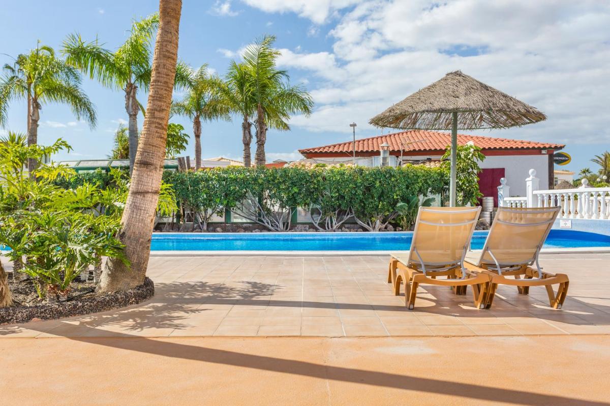 Dos sillas y una sombrilla junto a una piscina. en Royal Tenerife Country Club, en San Miguel de Abona