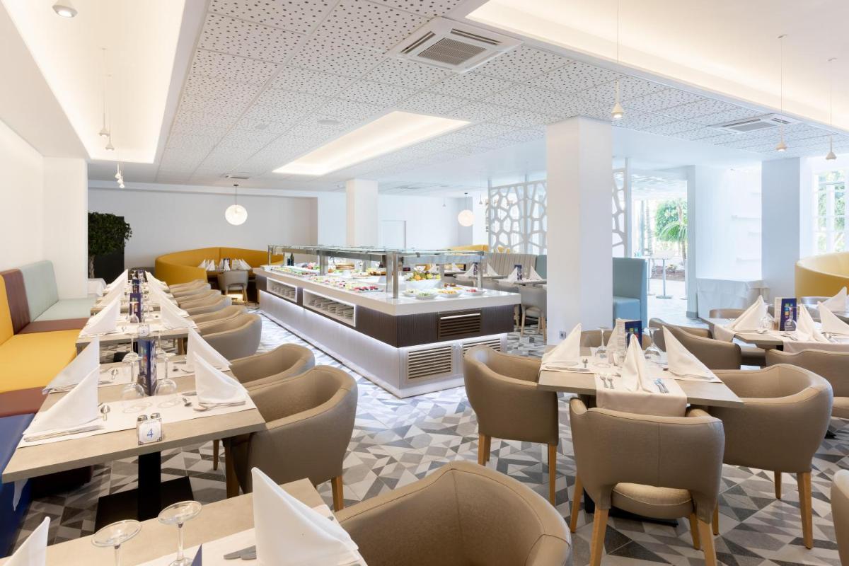 Un restaurante con mesas y sillas y un buffet. en Hotel Best Tenerife, en Playa de las Américas
