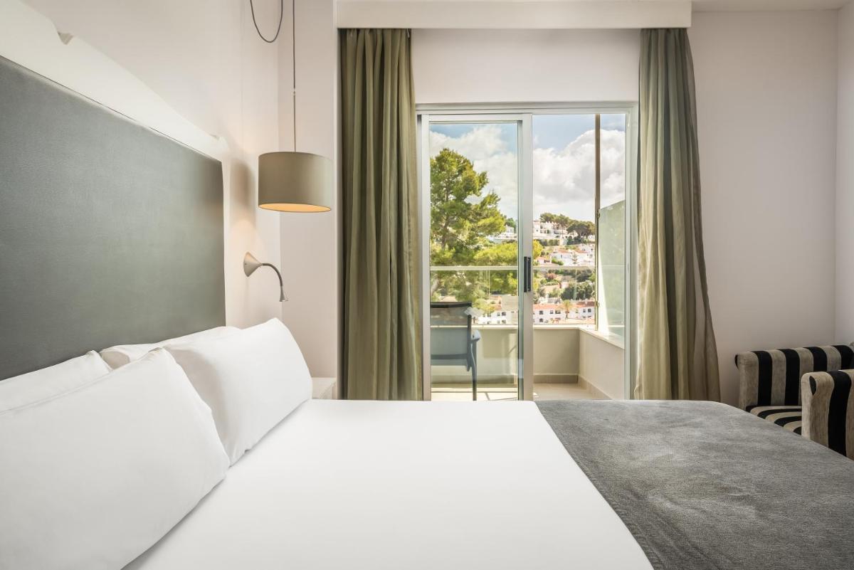 Un dormitorio con una cama blanca y una ventana. en ARTIEM Audax - Adults Only, en Cala Galdana