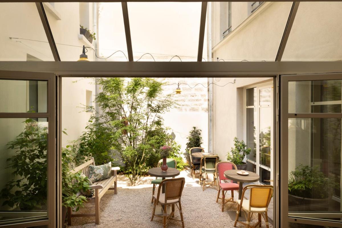 un patio avec tables et chaises dans un bâtiment dans l'établissement Le Petit Oberkampf Hotel & Spa, à Paris