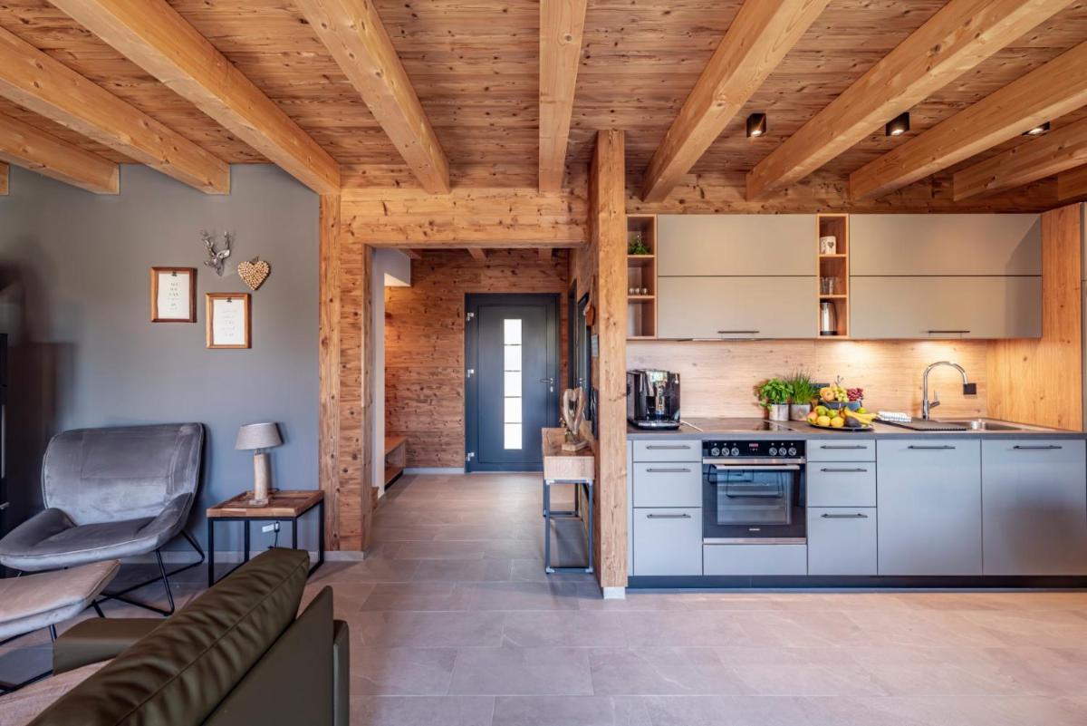 eine offene Küche und ein Wohnzimmer mit Holzdecken in der Unterkunft Vital CAMP Bayerbach in Bayerbach