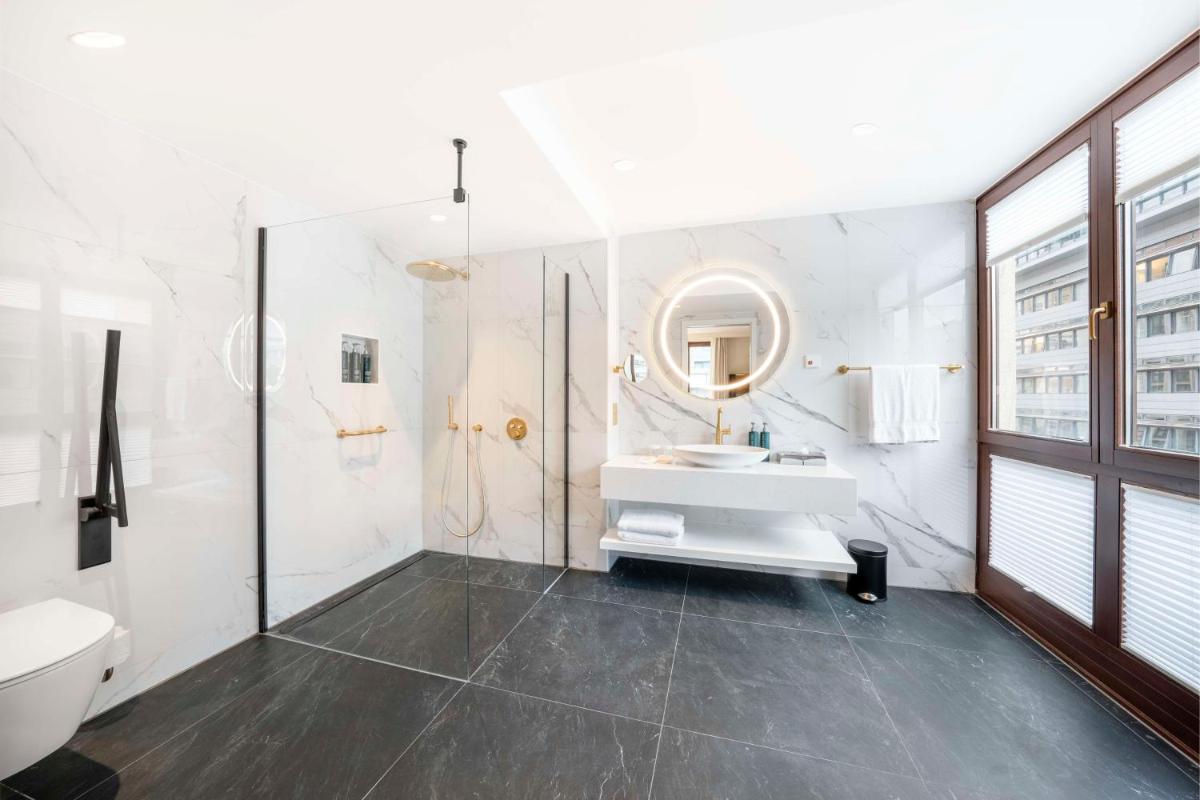 ein weißes Badezimmer mit Waschbecken und Spiegel in der Unterkunft Hilton Berlin in Berlin ein weißes Badezimmer mit Waschbecken und Spiegel in der Unterkunft Hilton Berlin in Berlin