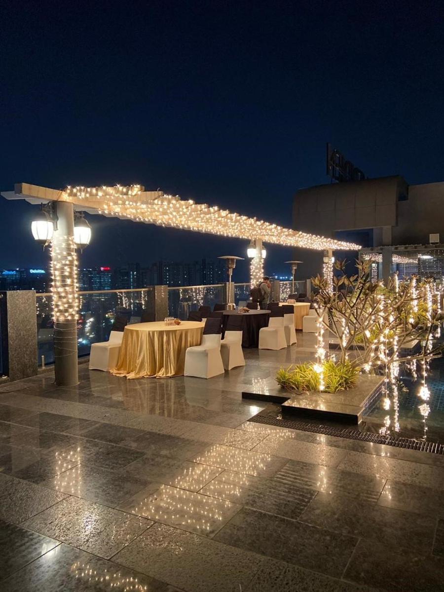 a patio with white tables and lights at night at Le Meridien Hyderabad in Hyderabad