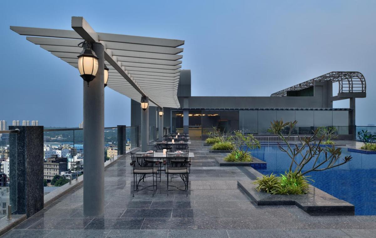a rooftop patio with tables and chairs on a building at Le Meridien Hyderabad in Hyderabad