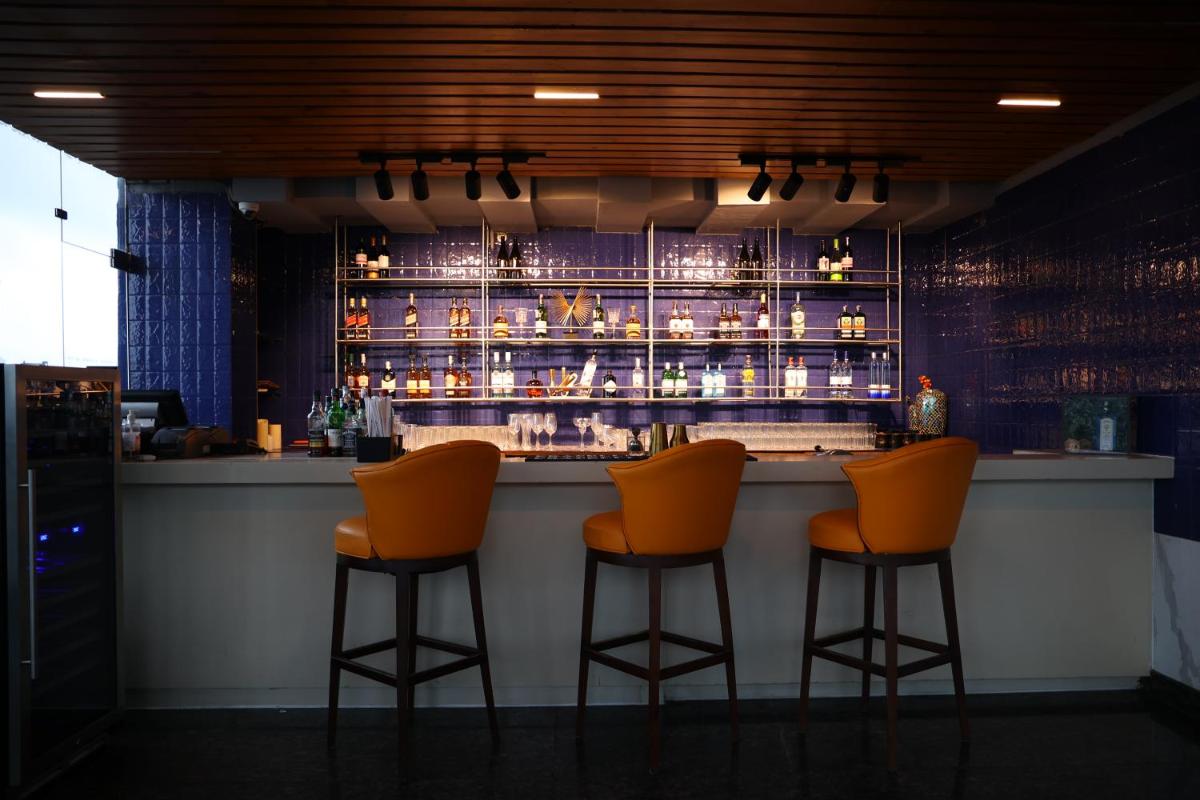 a bar with three orange bar stools in a room at Le Meridien Hyderabad in Hyderabad