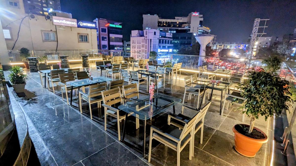 a restaurant with tables and chairs and a city at night at Le Meridien Hyderabad in Hyderabad