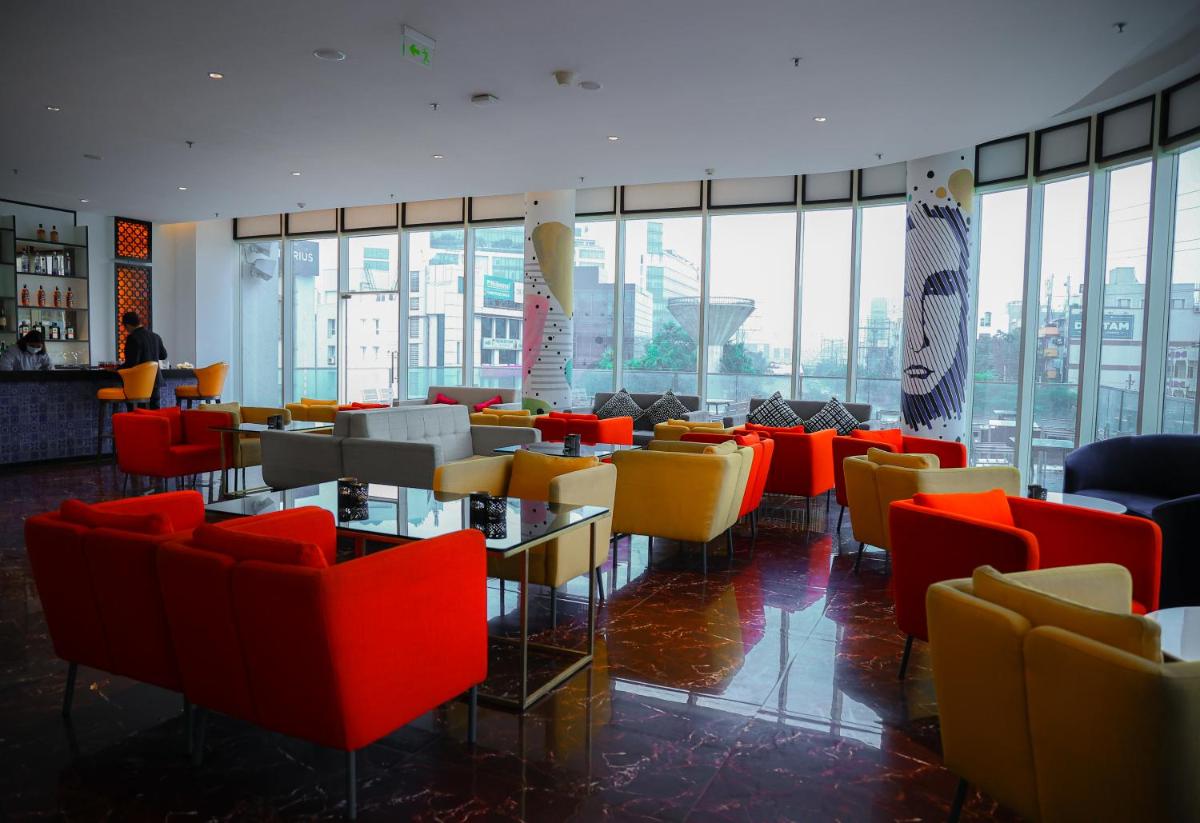 a restaurant with colorful chairs and tables and windows at Le Meridien Hyderabad in Hyderabad