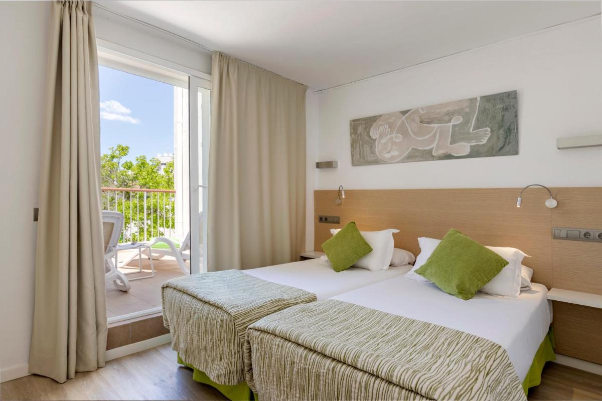 Una habitación de hotel con dos camas y balcón. en Houm Plaza Son Rigo, en Playa de Palma