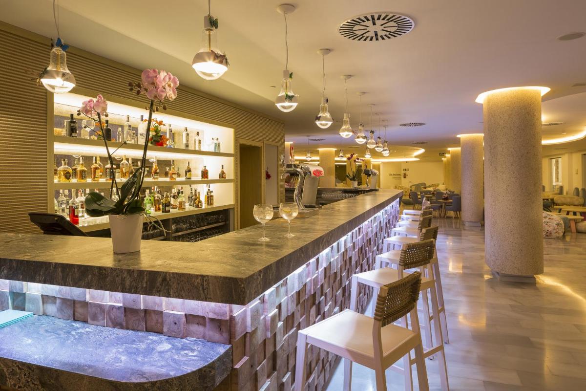 Un bar en un restaurante con sillas y mesas. en Grand Palladium White Island Resort & Spa - All Inclusive, en Playa d'en Bossa