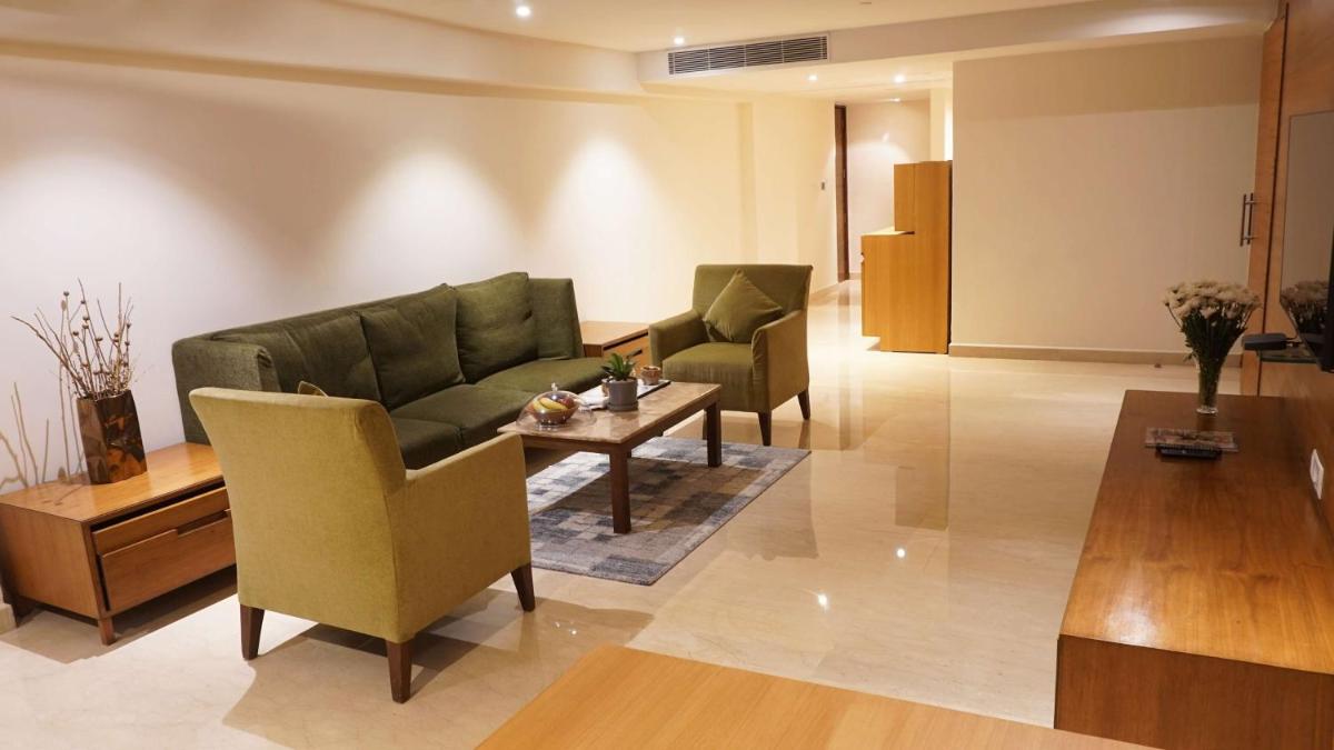 a living room with a couch and a table and chairs at Radisson Blu Plaza Hotel Hyderabad Banjara Hills in Hyderabad a living room with a couch and a table and chairs at Radisson Blu Plaza Hotel Hyderabad Banjara Hills in Hyderabad