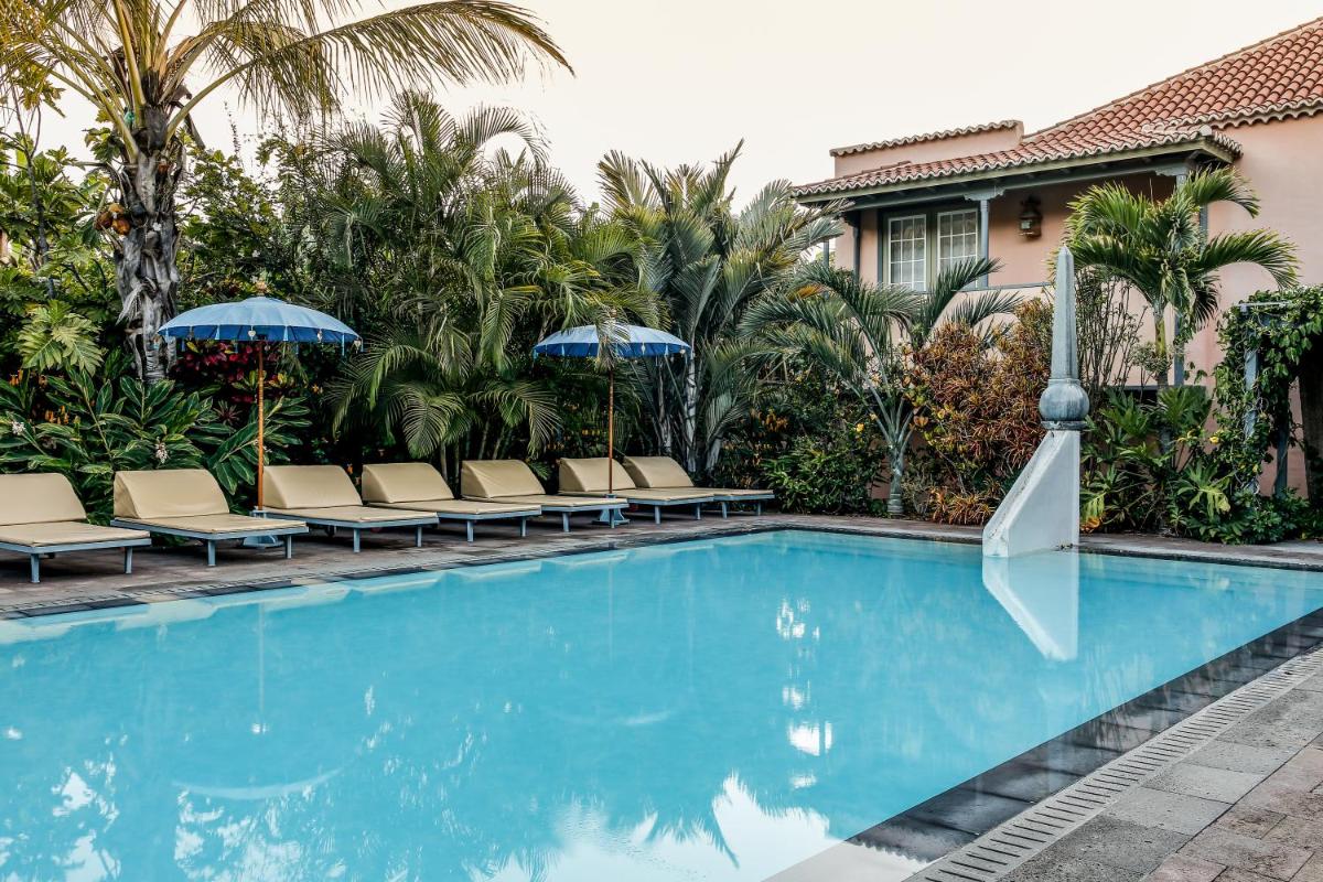 Una piscina con sillas y sombrillas al lado de una casa. en Hotel Hacienda de Abajo-Adults Only-Lujo, en Tazacorte