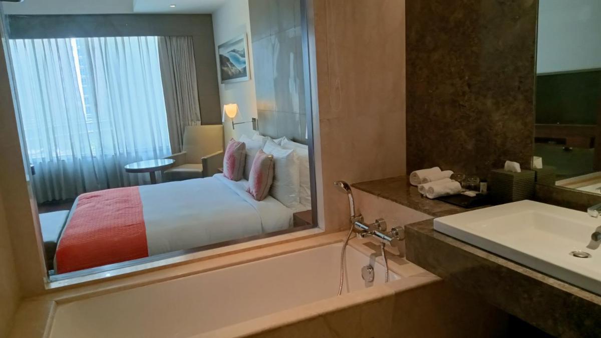 a bathroom with a bed and a tub and a sink at The Anya Hotel-Golf Course Road in Gurgaon