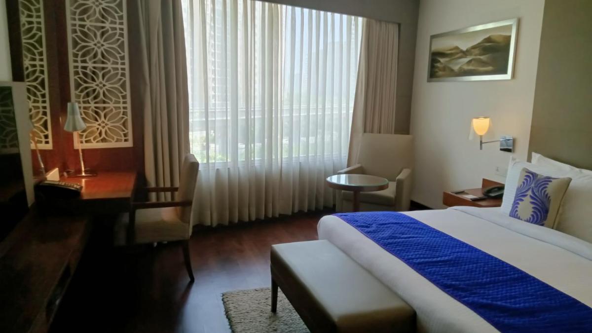a hotel room with a bed and a desk and a window at The Anya Hotel-Golf Course Road in Gurgaon