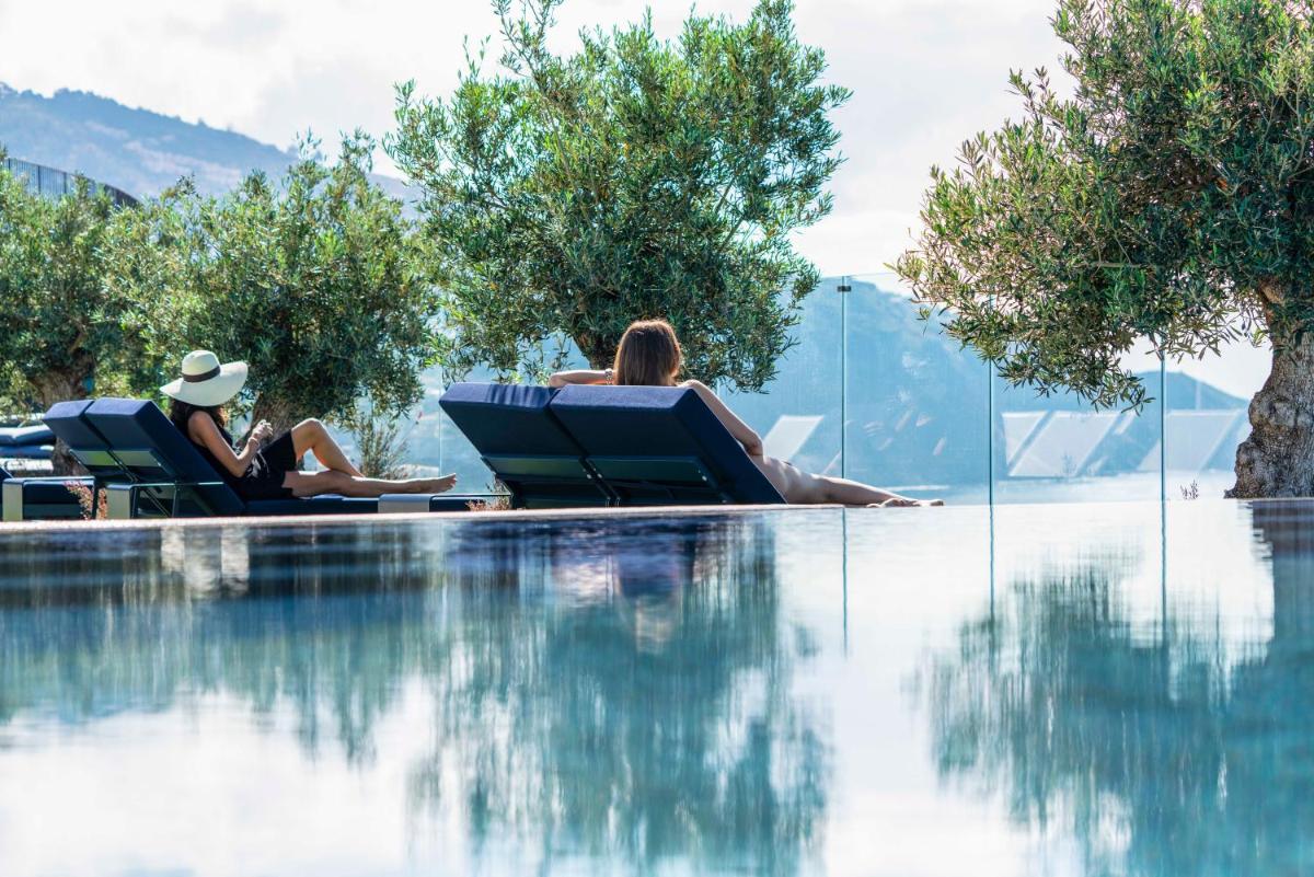 duas mulheres deitadas em espreguiçadeiras ao lado de uma piscina em The Reserve - within Savoy Palace - The Leading Hotels of the World no Funchal