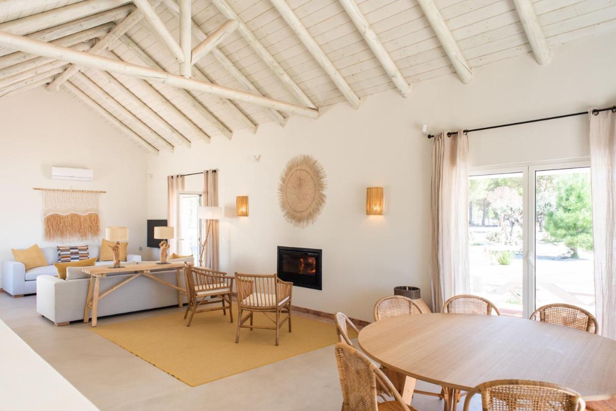 uma sala de estar com uma mesa e um sofá em Independente Comporta na Comporta