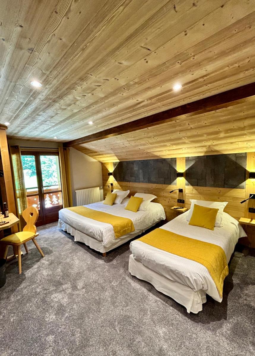 Cette chambre spacieuse dispose de 2 lits et de plafonds en bois. dans l'établissement Hameau des Prodains - Hôtel, à Morzine
