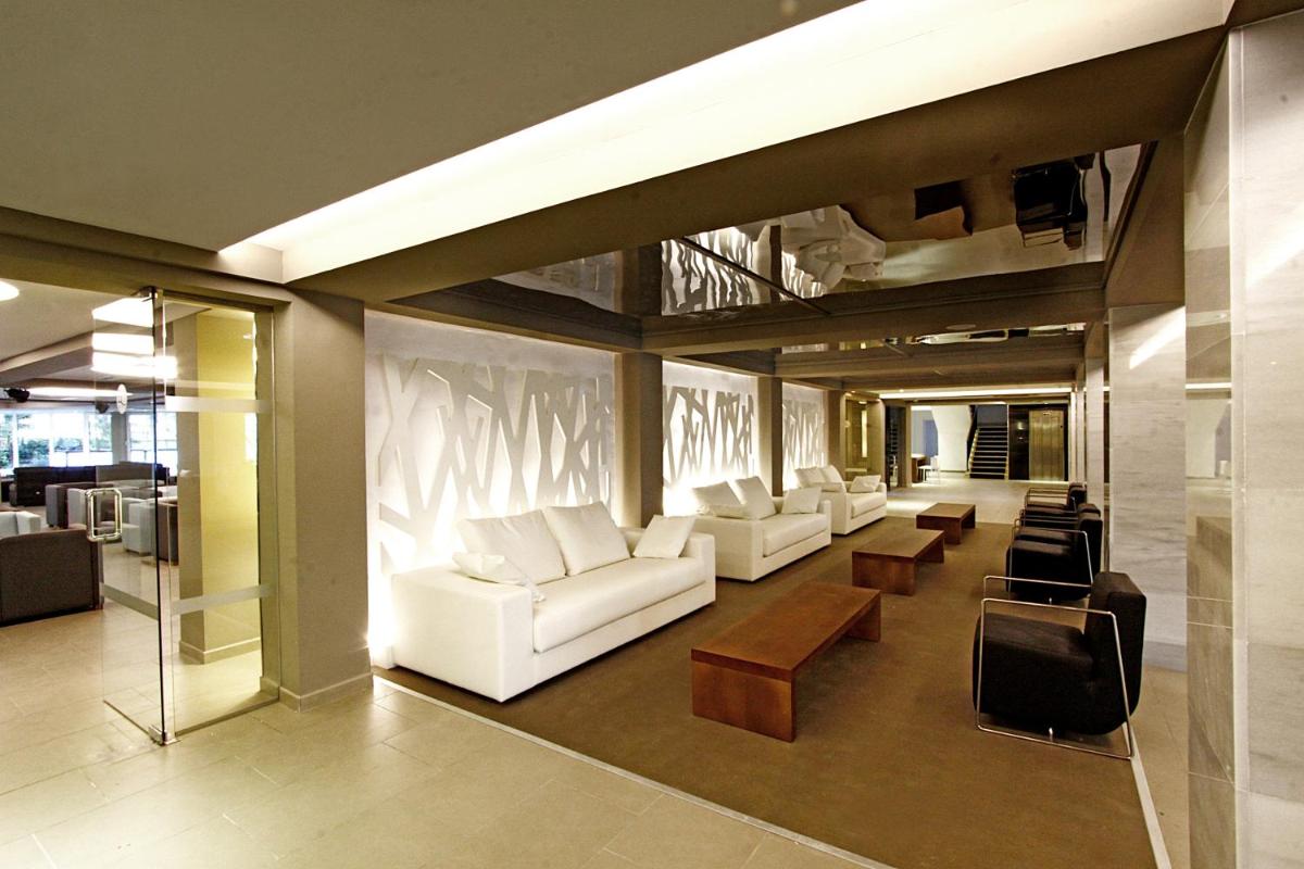 una sala de estar con sofás blancos, sillas y mesas. en BG Java, en Can Pastilla