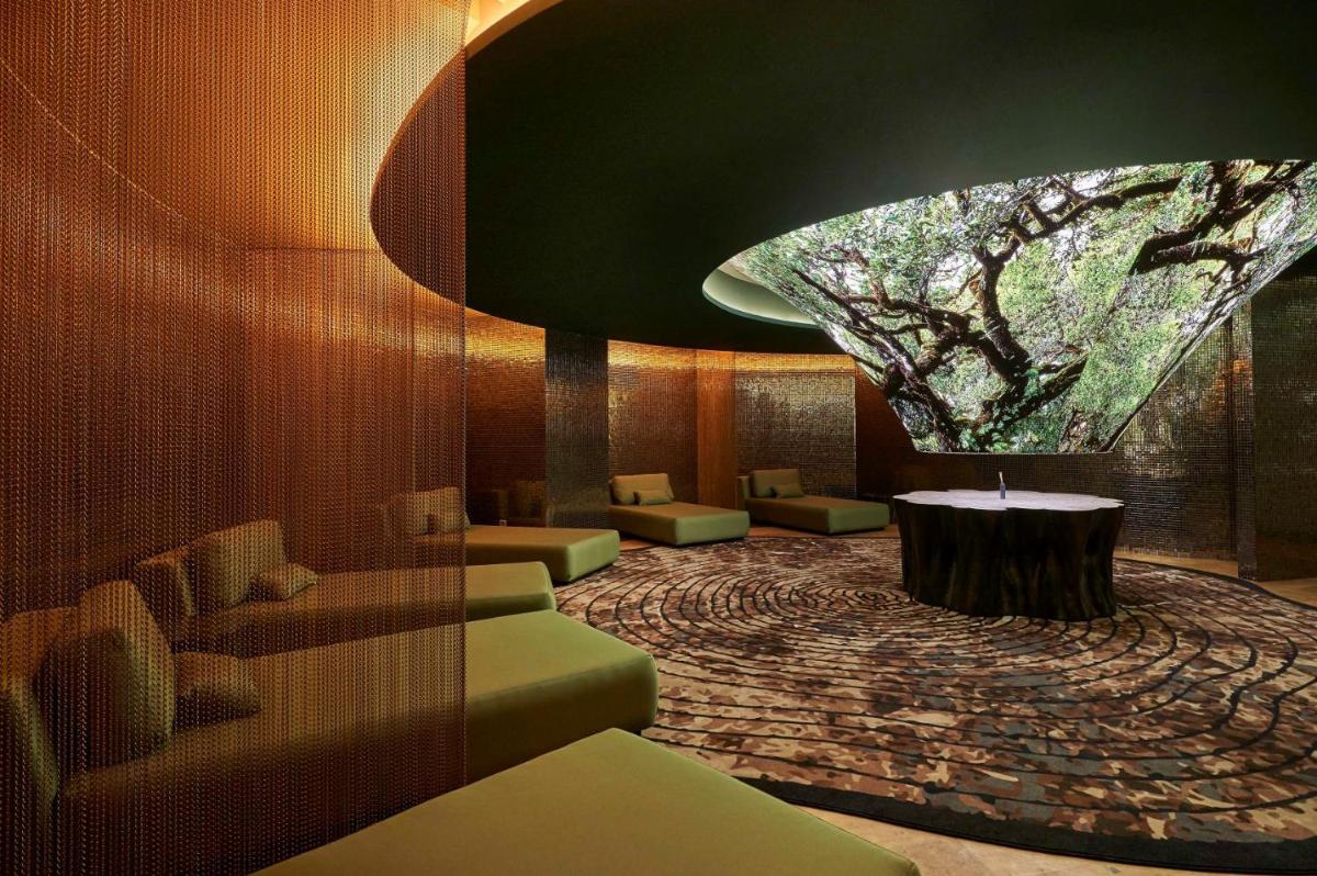 um átrio com uma árvore e cadeiras e uma mesa em The Reserve - within Savoy Palace - The Leading Hotels of the World no Funchal
