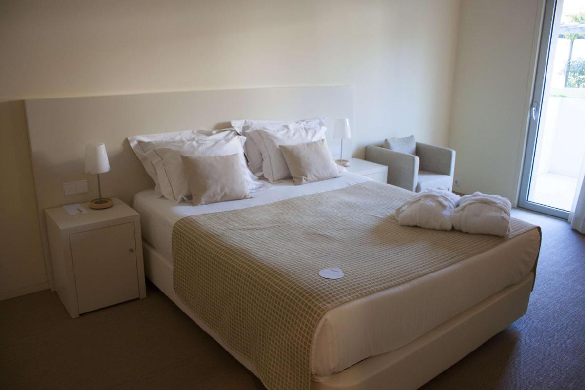 um quarto com uma cama grande com lençóis e travesseiros brancos em INLIMA Hotel & Spa em Ponte de Lima mais 42 fotografias