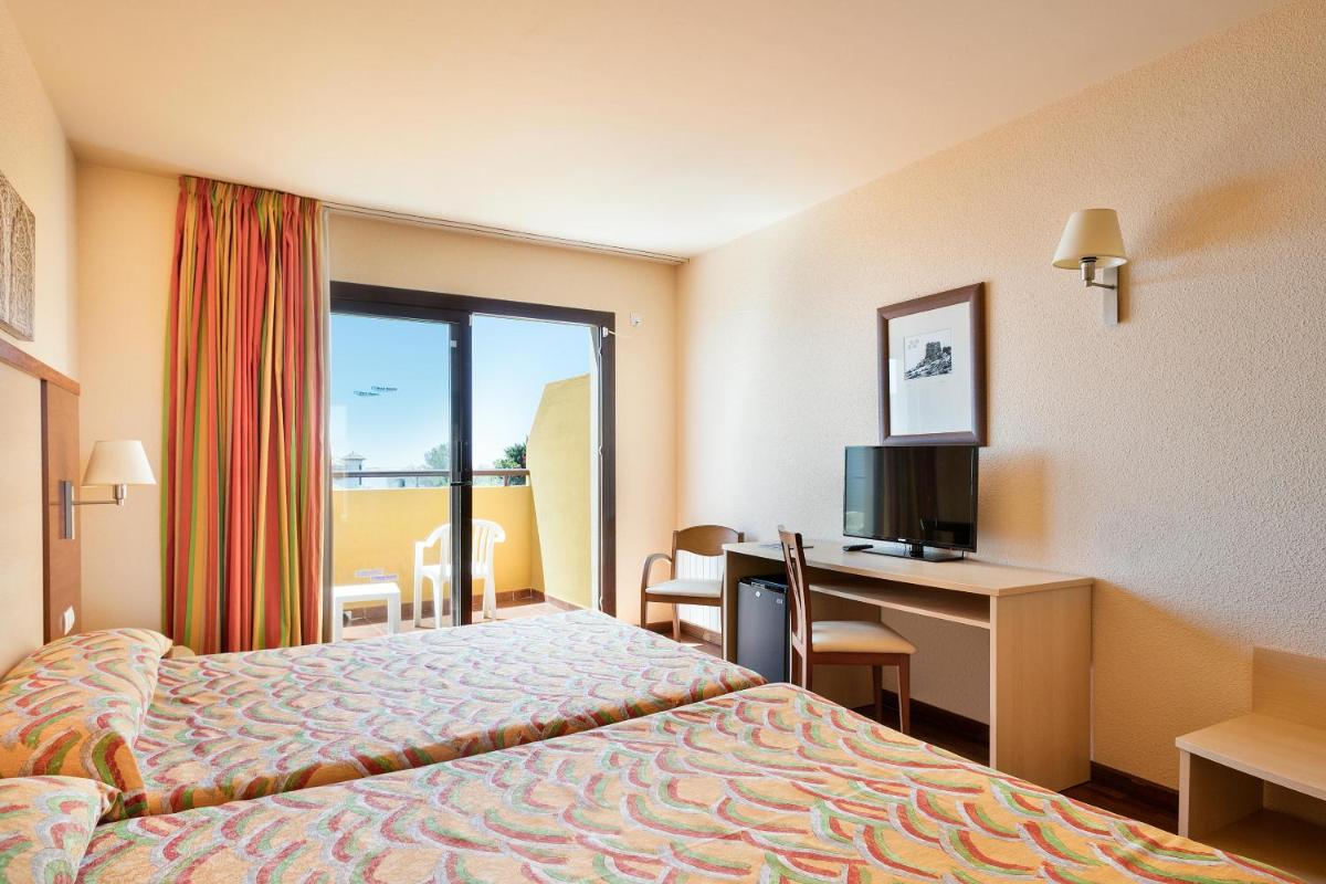 Una habitación de hotel con una cama, un escritorio y un televisor. en Hotel Best Alcázar, en La Herradura