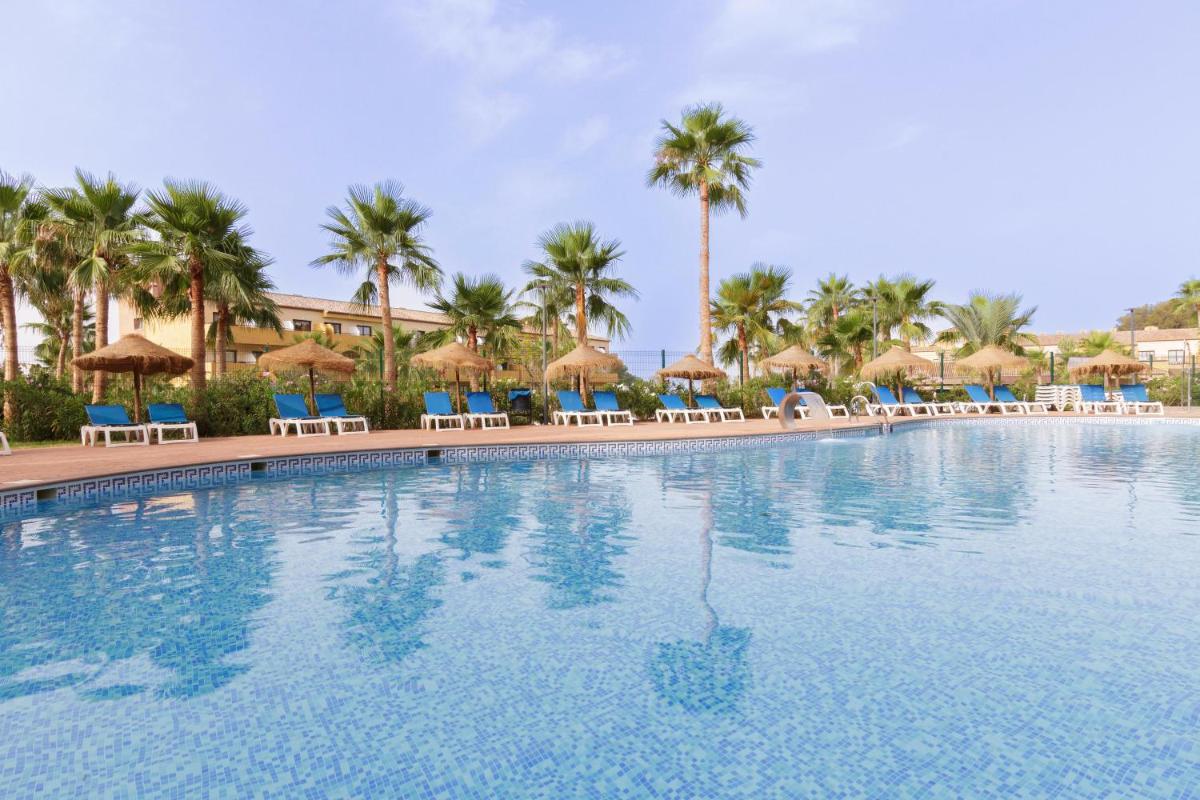 una gran piscina con sillas y sombrillas en Apartamentos Best Alcazar, en La Herradura