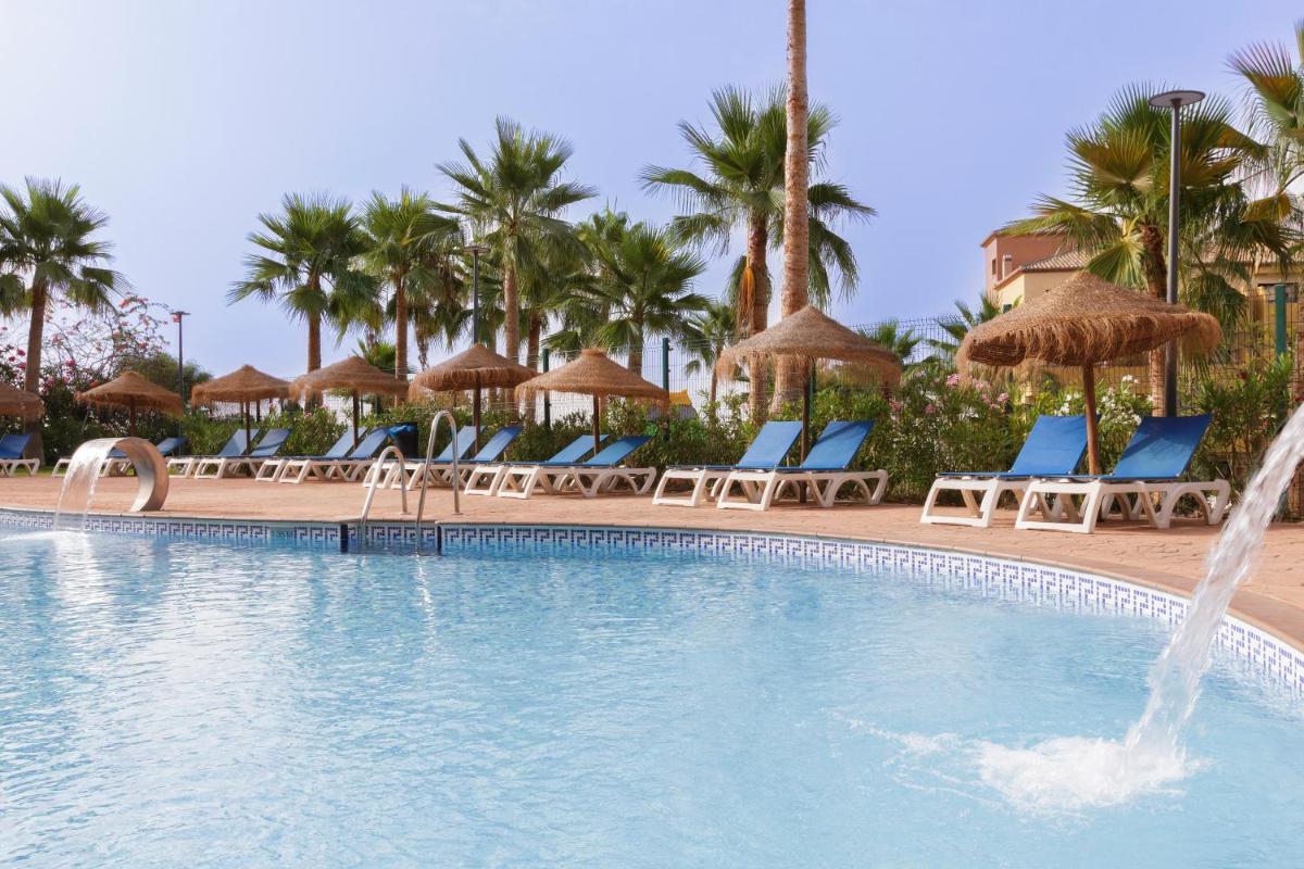 una piscina en un resort con sillas y sombrillas en Apartamentos Best Alcazar, en La Herradura