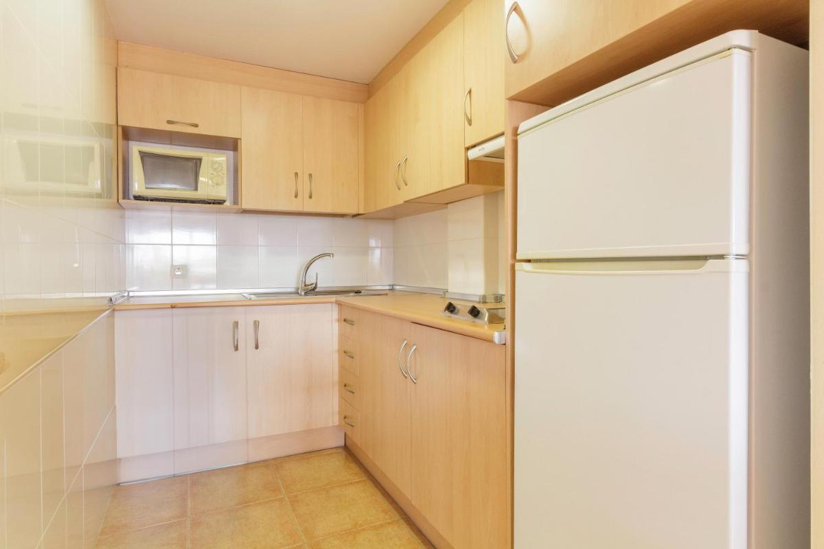 Una cocina con gabinetes de madera y un refrigerador blanco. en Apartamentos Best Alcazar, en La Herradura