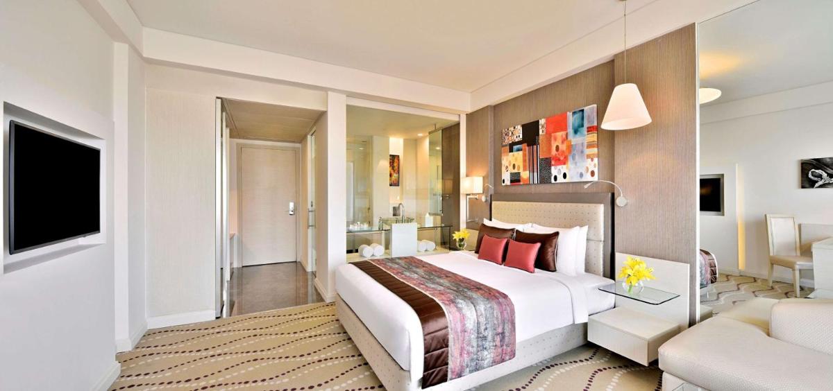 a bedroom with a large bed and a living room at Radisson Blu Bengaluru Outer Ring Road in Bengaluru