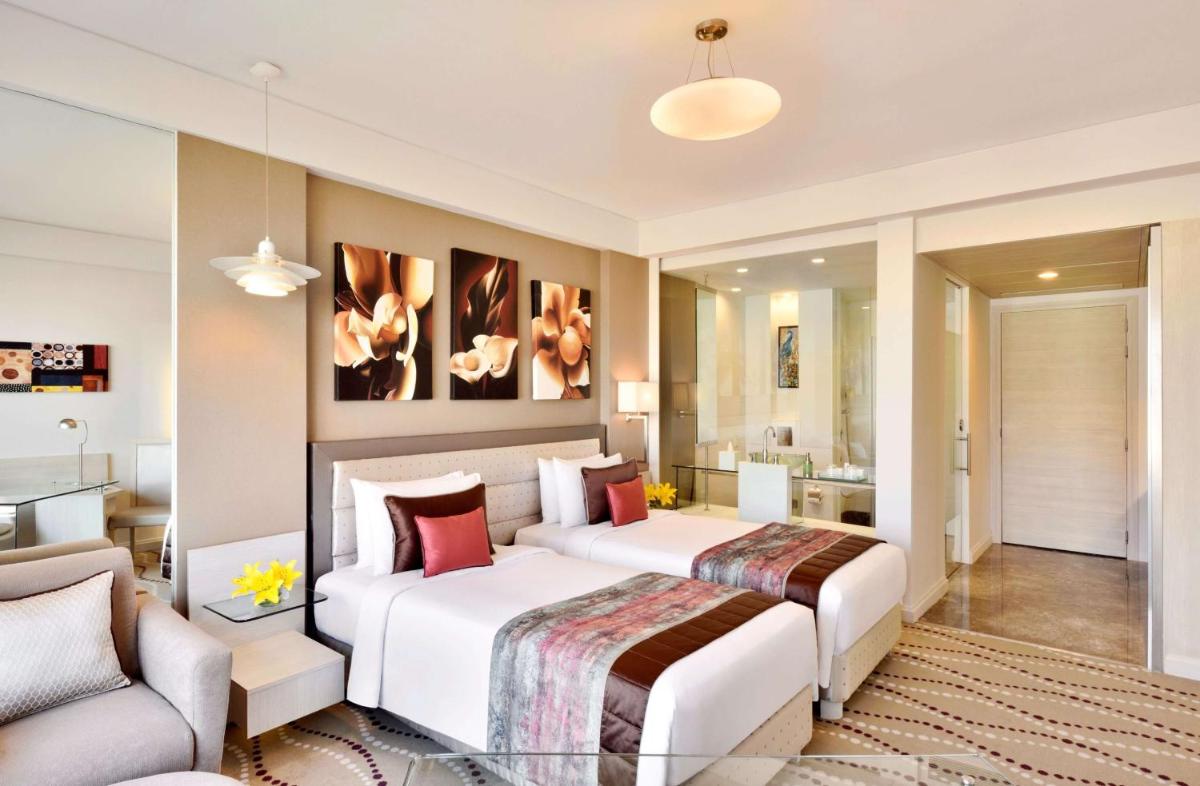 a bedroom with two beds and a living room at Radisson Blu Bengaluru Outer Ring Road in Bengaluru