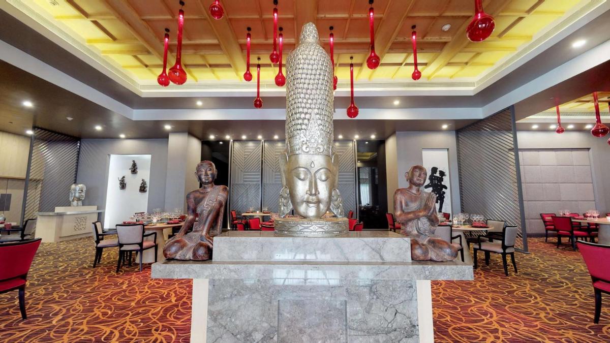 a restaurant with a large statue in the middle of a room at Radisson Blu Bengaluru Outer Ring Road in Bengaluru