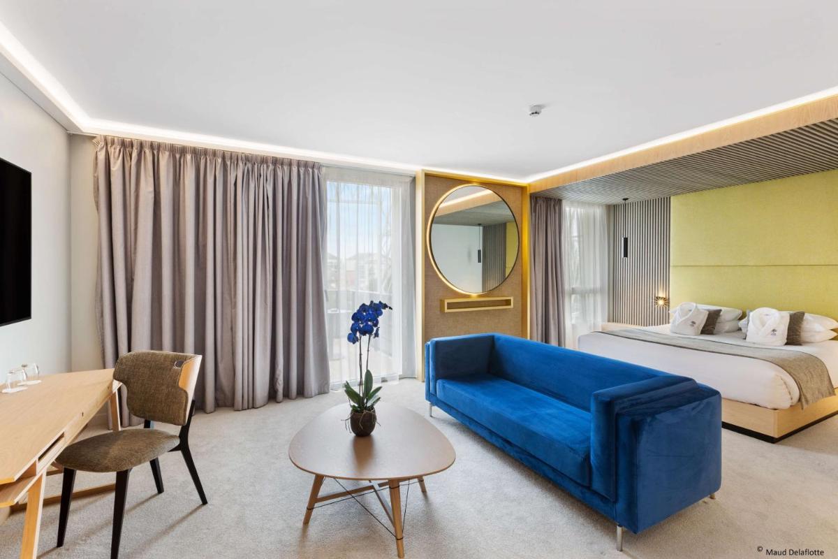 une chambre d'hôtel avec un canapé bleu et un lit dans l'établissement Aiden by Best Western T'aim Hotel & SPA, à Compiègne
