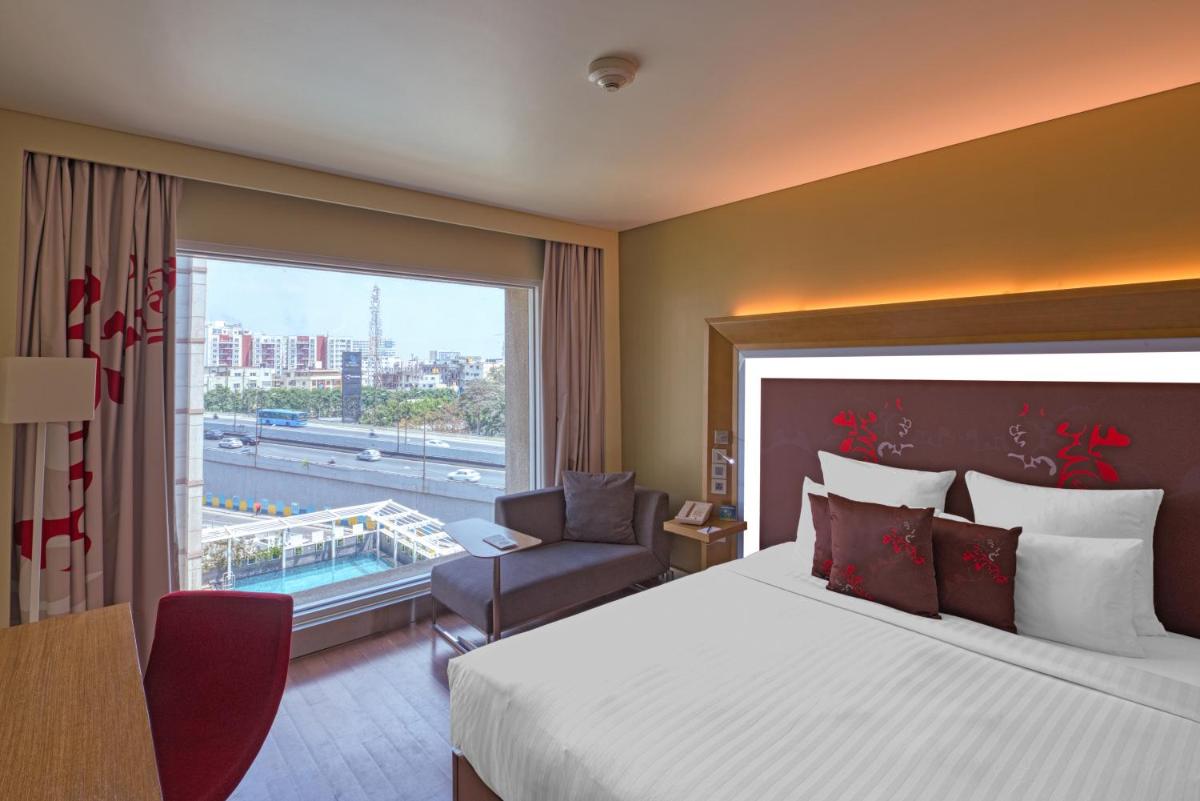 a hotel room with a large bed and a window at Novotel Bengaluru Outer Ring Road in Bengaluru