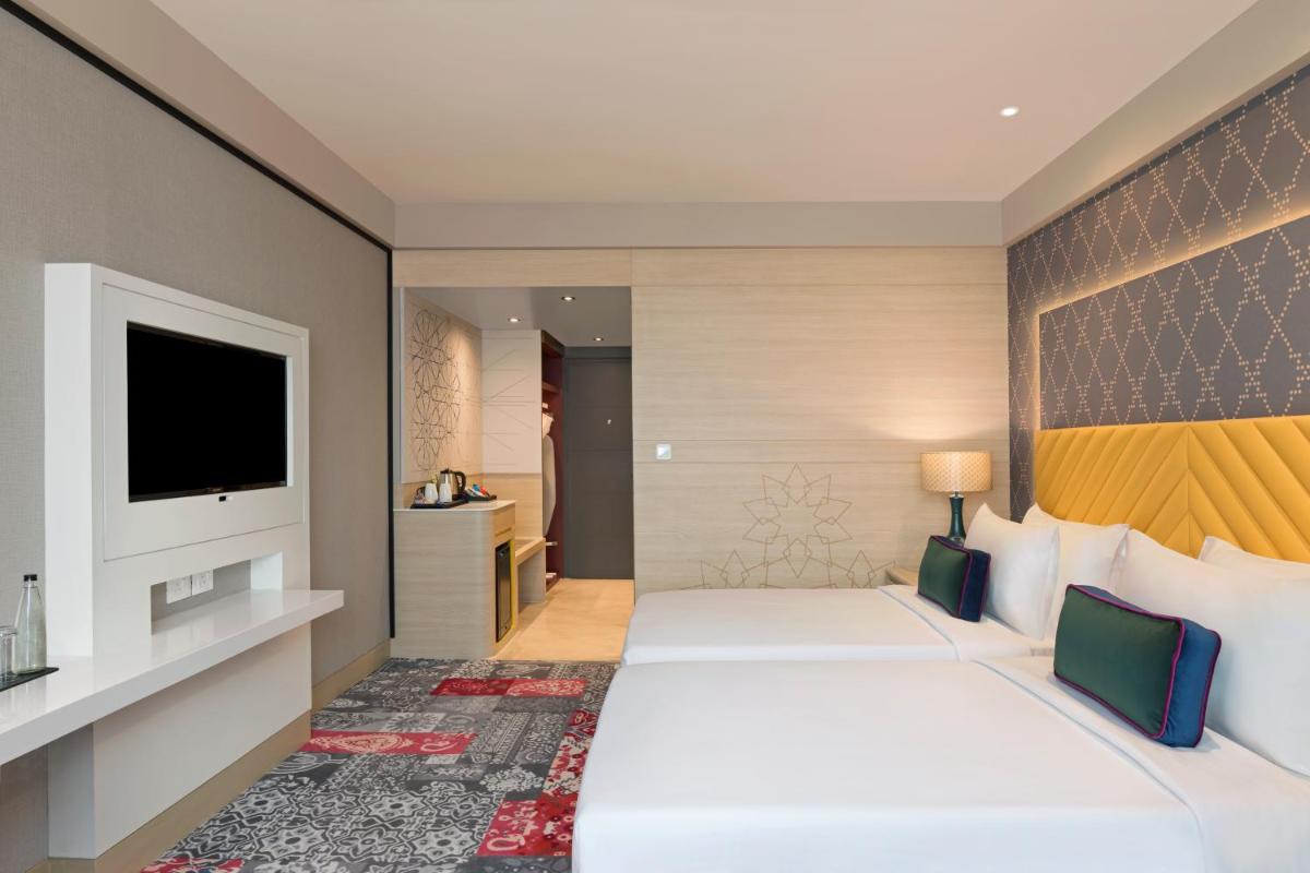 a hotel room with two beds and a television at Grand Mercure Agra - An Accor Brand in Agra
