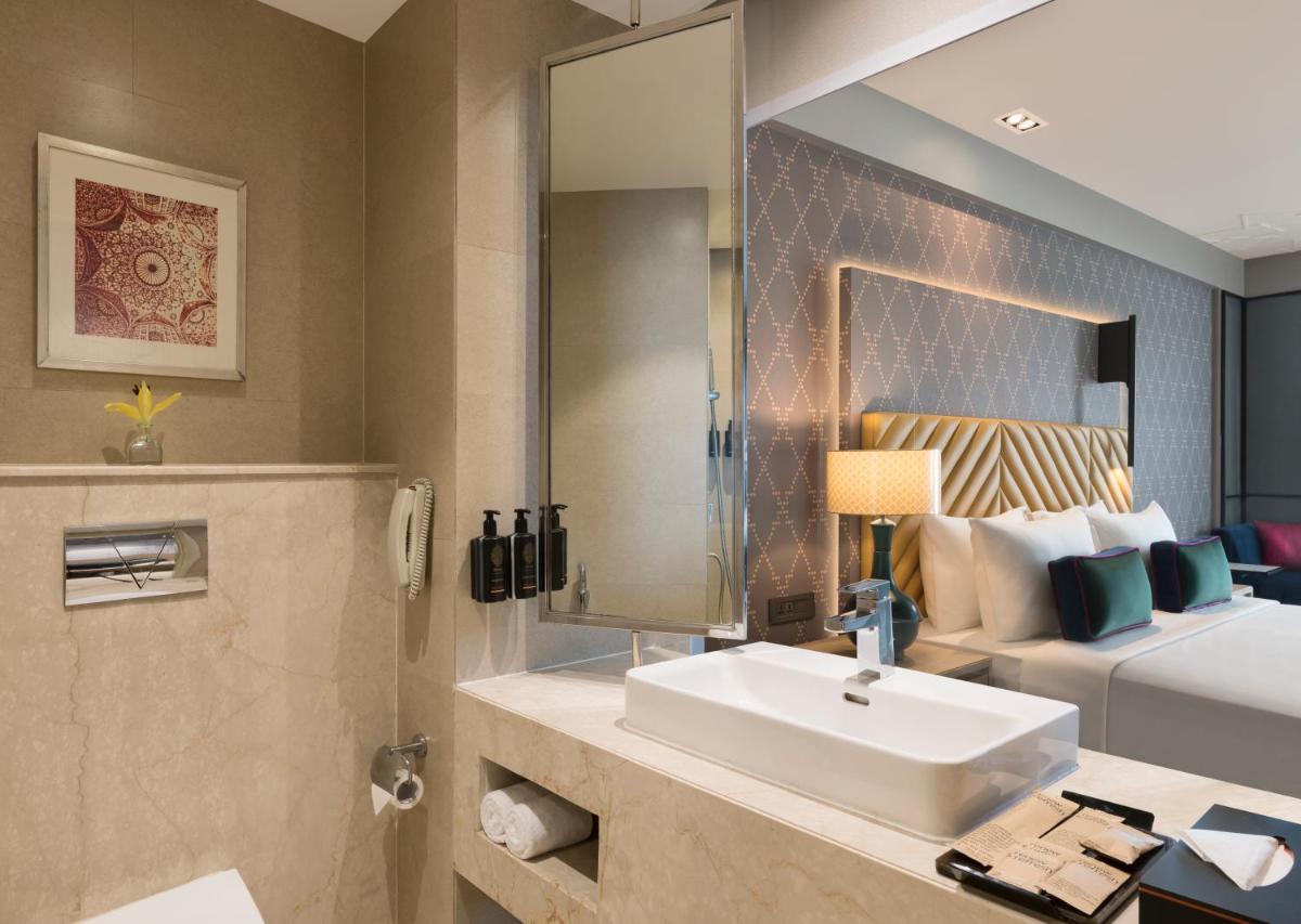 a bathroom with a sink and a bed and a mirror at Grand Mercure Agra - An Accor Brand in Agra