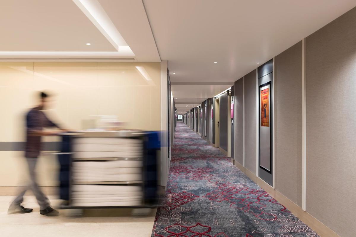 a man walking down a hallway in an office building at Grand Mercure Agra - An Accor Brand in Agra