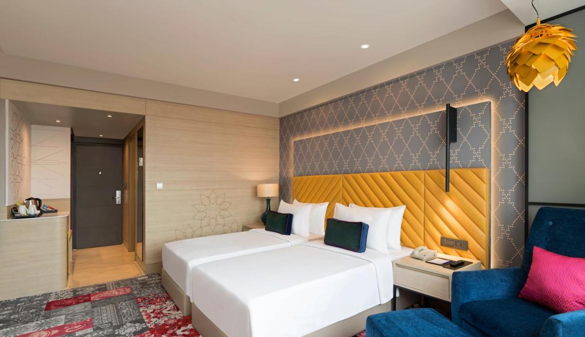 a bedroom with a white bed and a blue chair at Grand Mercure Agra - An Accor Brand in Agra