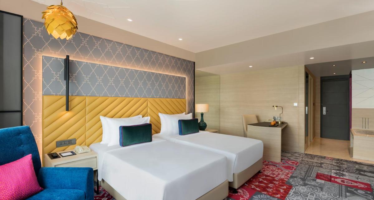 a bedroom with a large white bed and a blue chair at Grand Mercure Agra - An Accor Brand in Agra