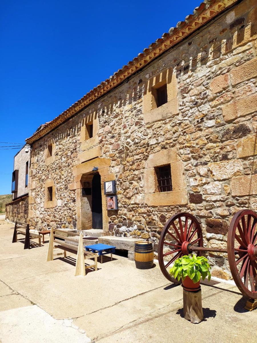 un edificio de piedra con bancos y una mesa azul delante de él en Posada Real La Vieja Chimenea-Spa, en Herreros