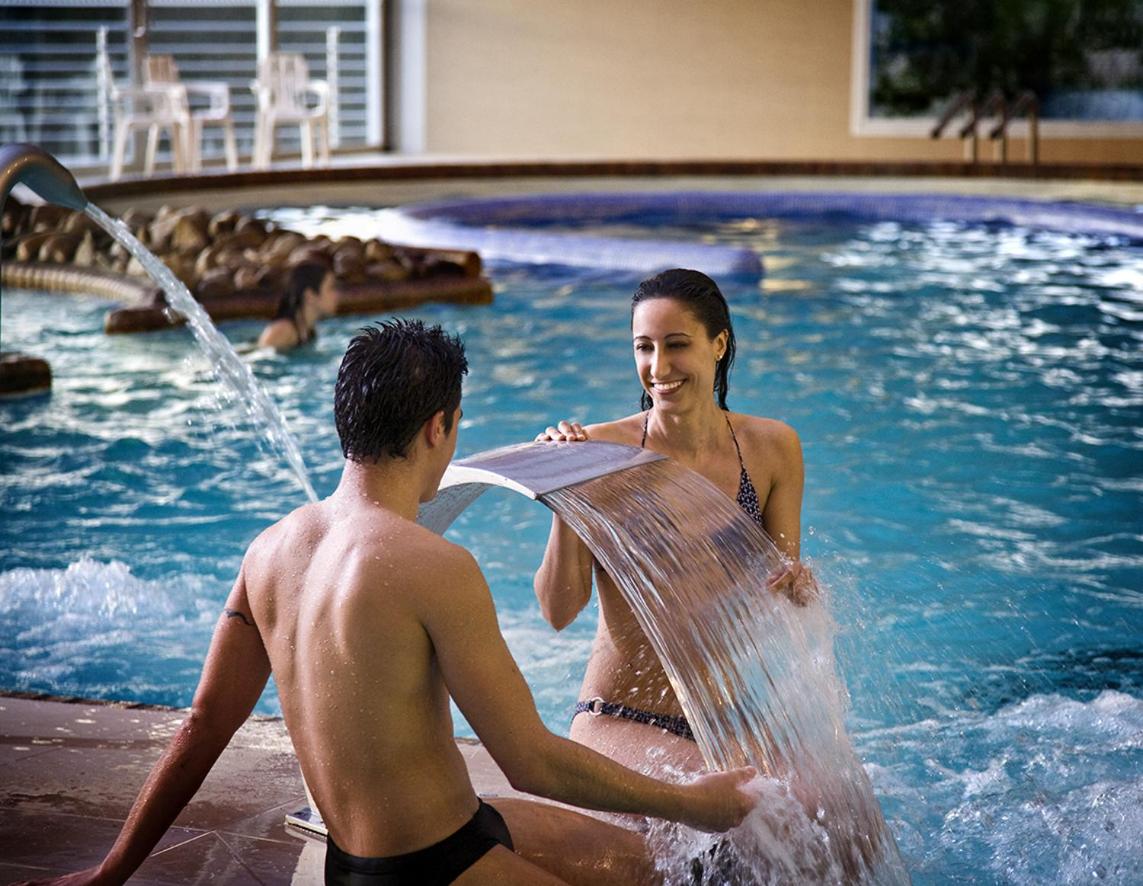 un hombre y una mujer jugando en una piscina en ARNOIA CALDARIA HOTEL Y BALNEARIO, en Arnoia