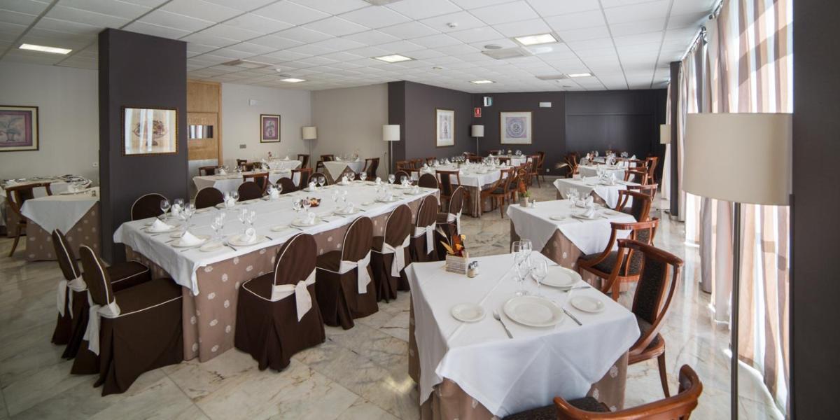 Un comedor con mesas y sillas blancas. en ARNOIA CALDARIA HOTEL Y BALNEARIO, en Arnoia